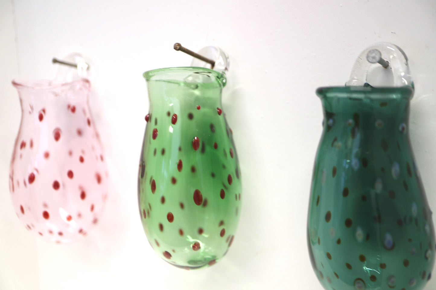 three different colored wall vases hanging in a line 